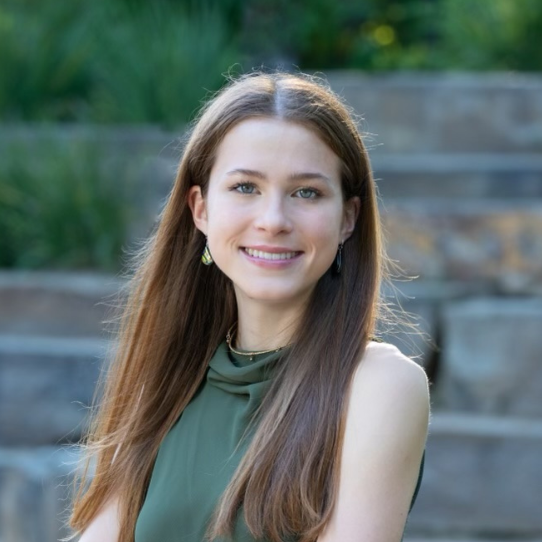 A woman with very long, straight, brown hair is smiling at the camera.