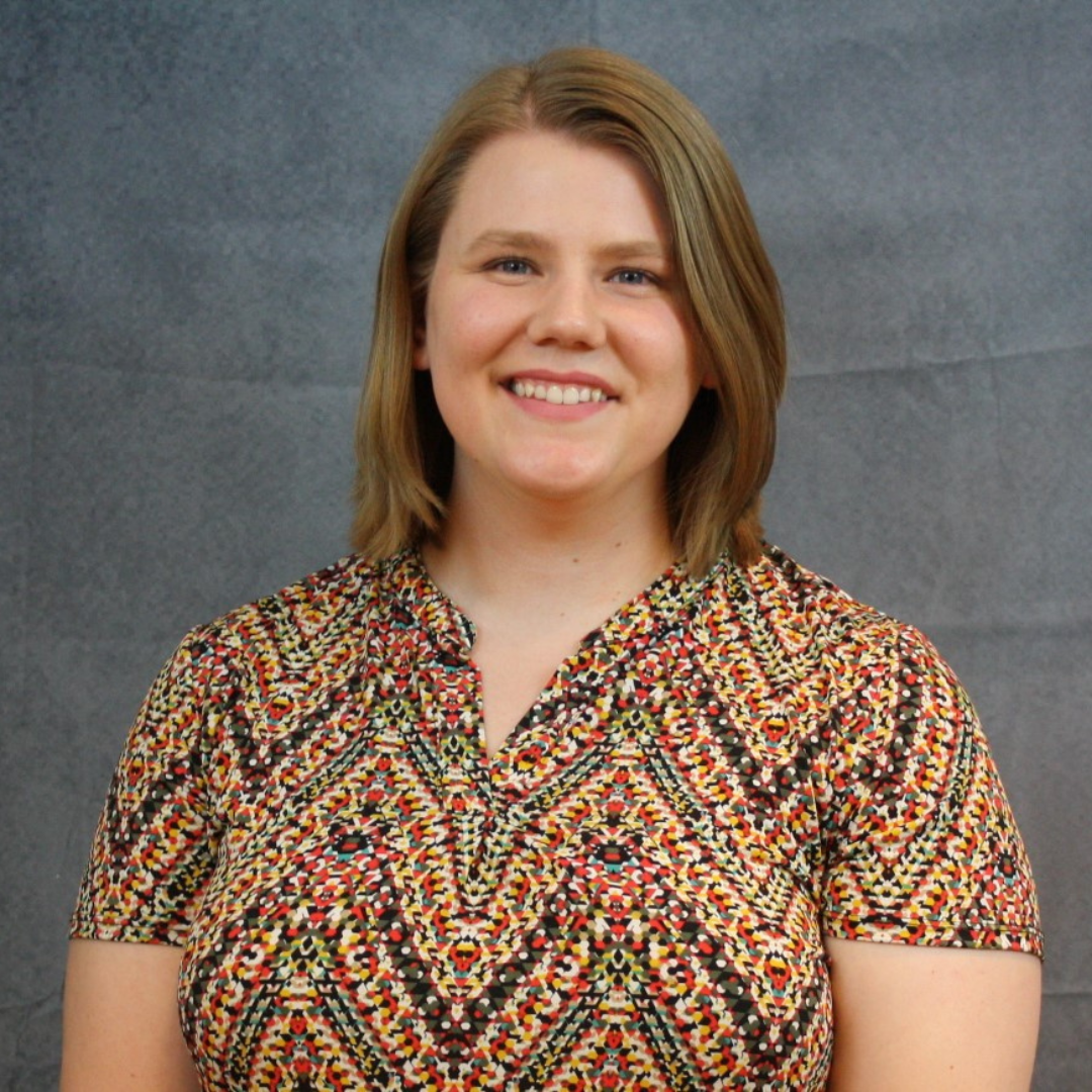 A woman with shoulder length, dark blonde hair is seen smiling at the camera